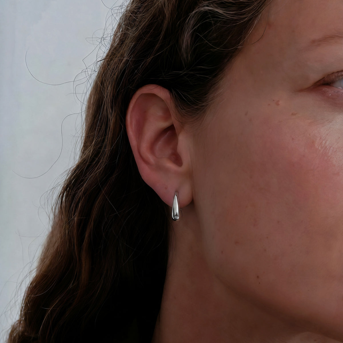 Model wearing Silent Palm sterling silver hook earrings.