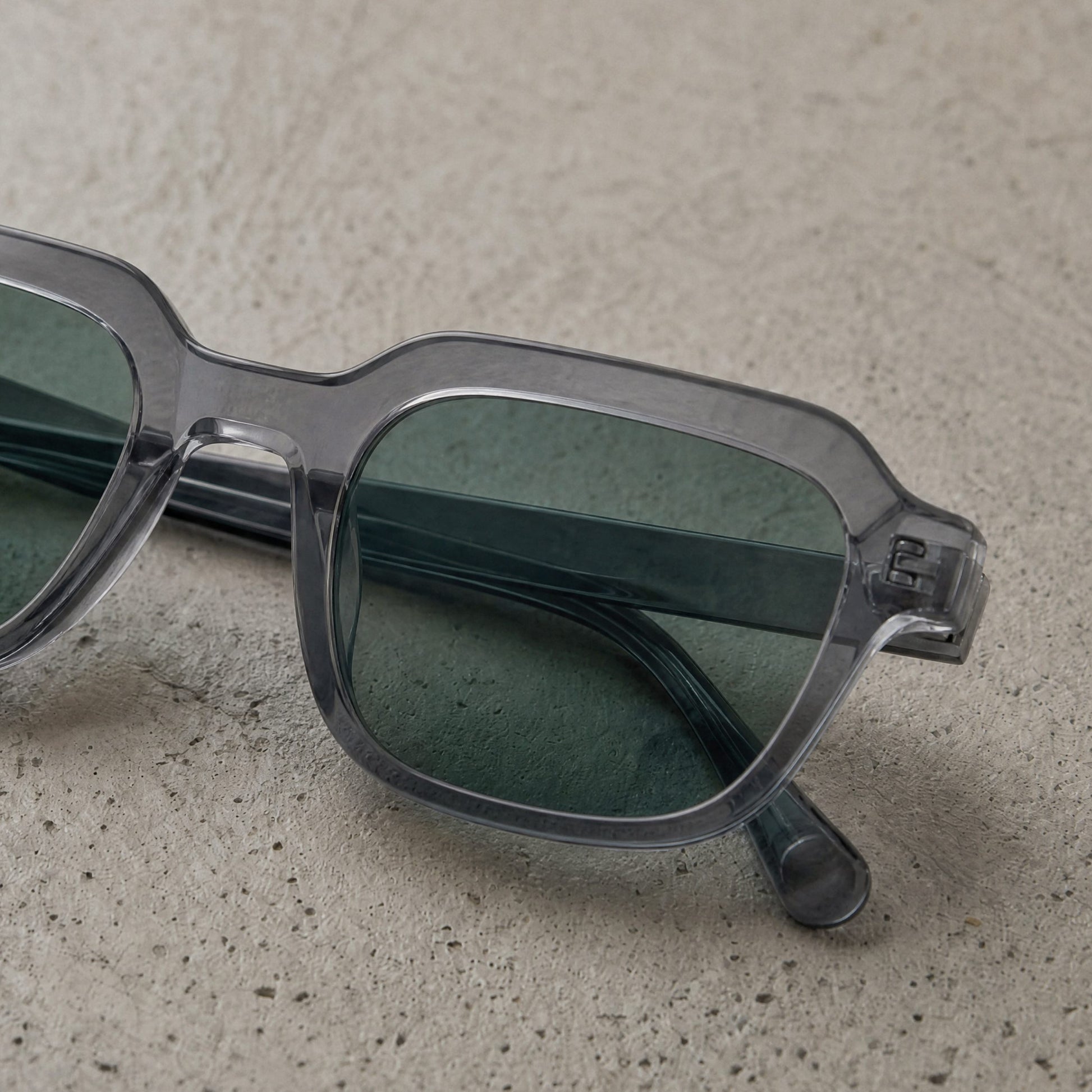Gradient lens acetate sunglasses resting on textured stone surface