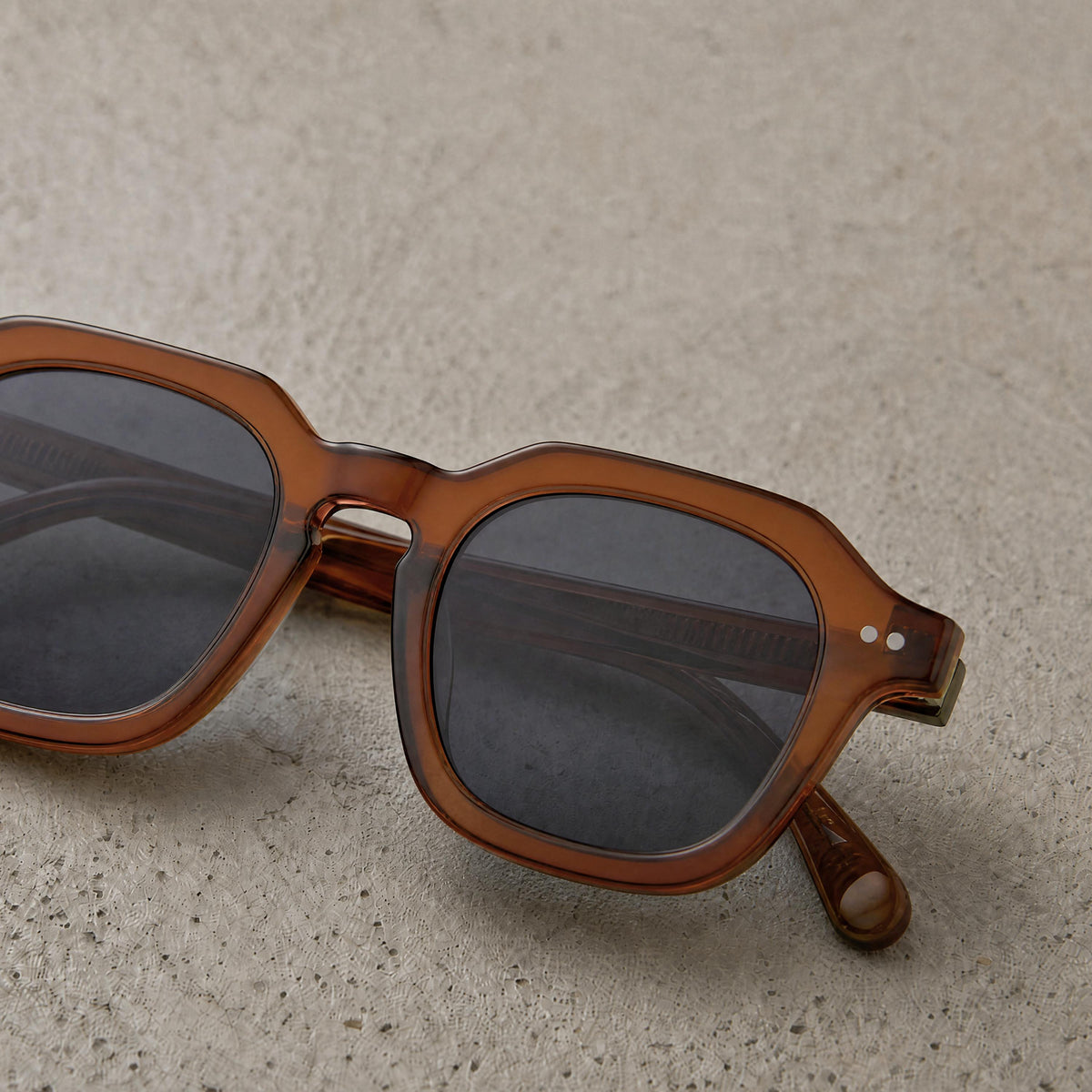 Amber translucent sunglasses resting on textured stone surface