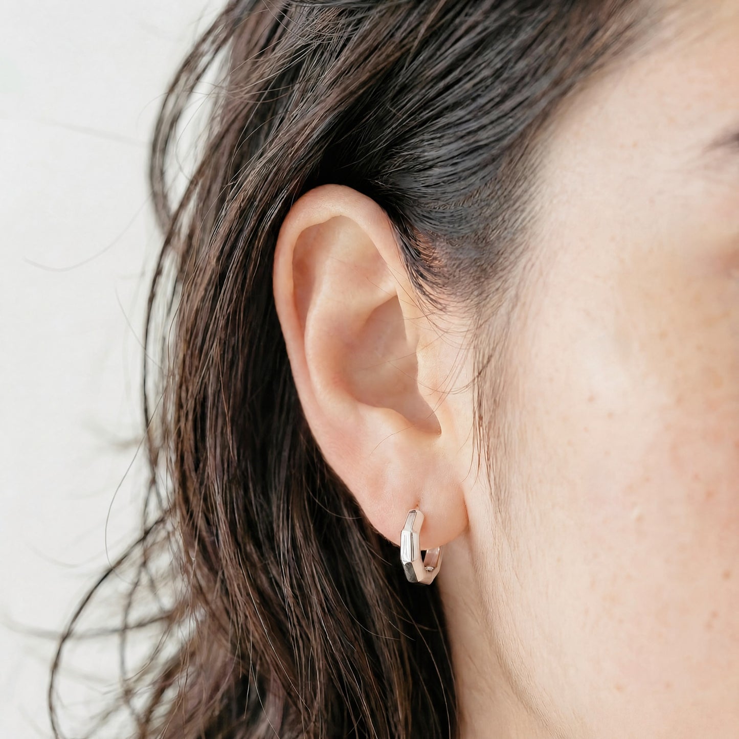 Model wearing Wishing Coin sterling silver hoop earrings.