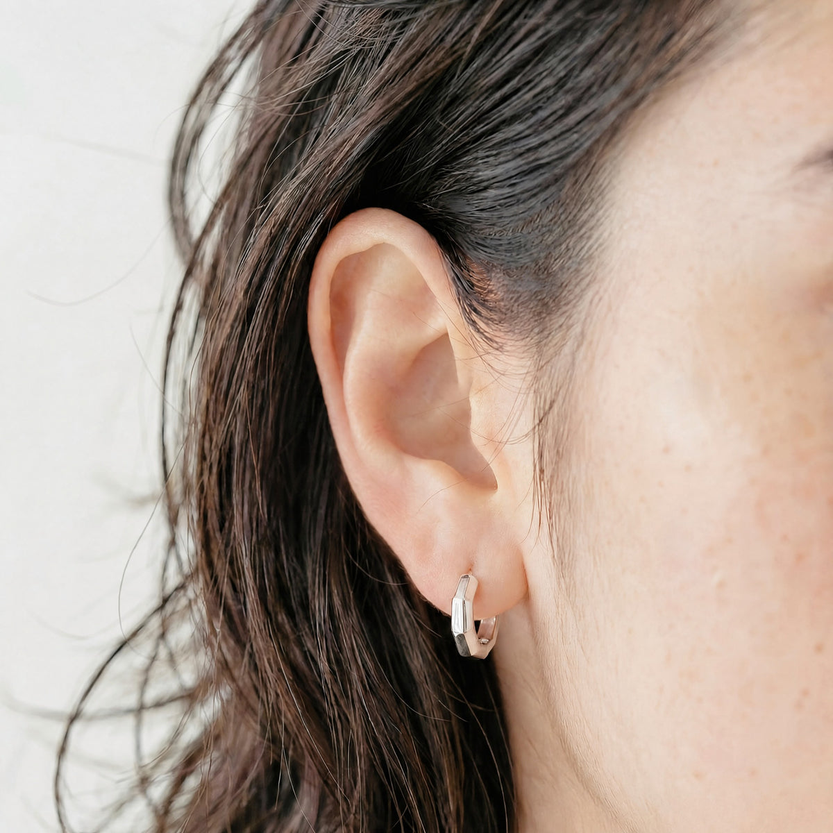 Model wearing Wishing Coin sterling silver hoop earrings.