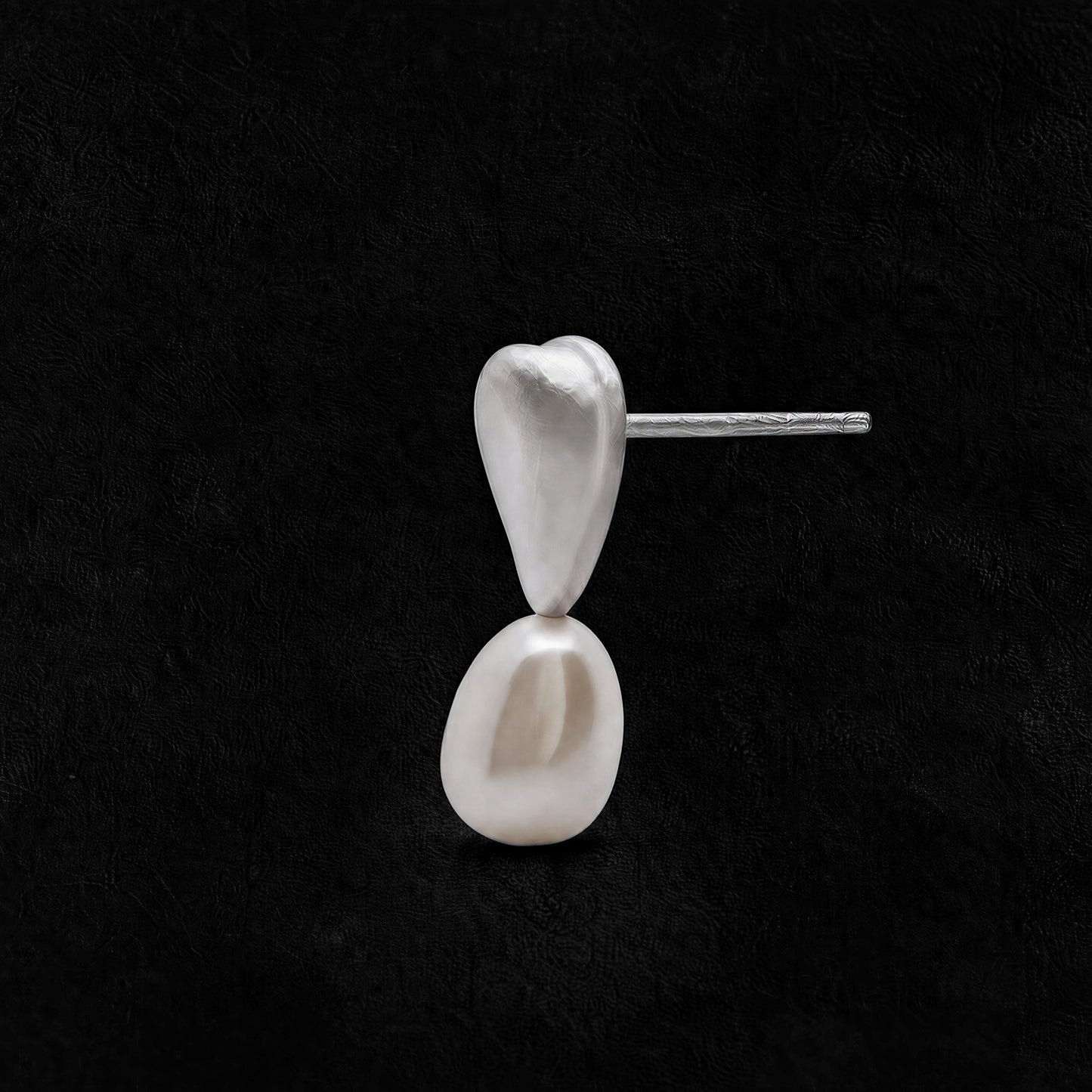 Still Pearl freshwater pearl earrings with a sculptural sterling silver setting on a black background.