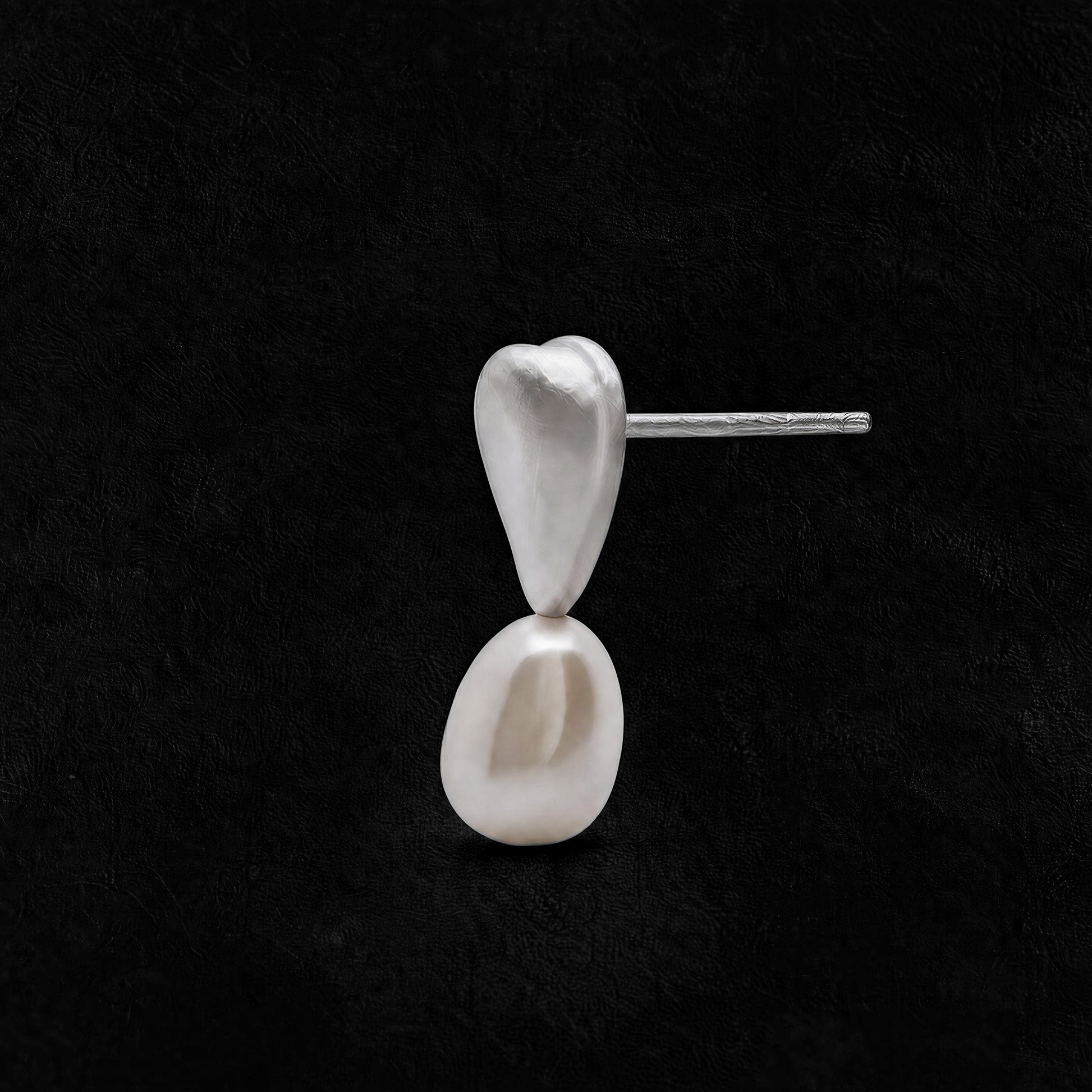 Still Pearl freshwater pearl earrings with a sculptural sterling silver setting on a black background.